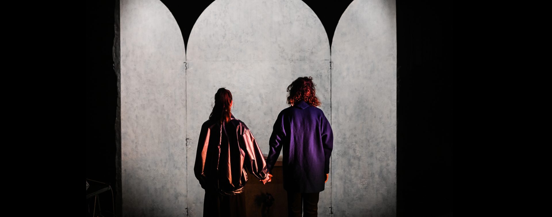 deux femmes de dos, se tenant la main devant un autel
