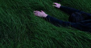 un homme allongé dans l'herbe, comme pour embrasser la terre sous lui